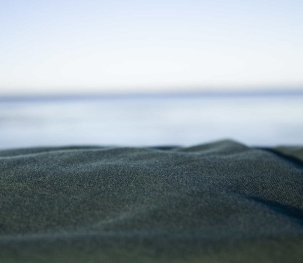 Detailaufnahme eines dunkelgrünen Spannbettlakens am Meer