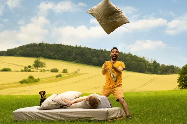 Ein Bett mit Bio-Bettwaesche von noca auf einem Feld mit dem Gründer Ergin Sakoglu.
