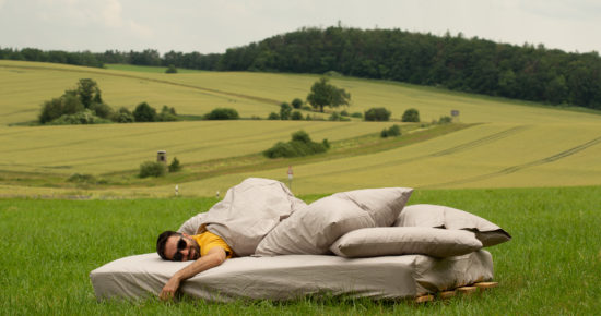 Mann liegt in Bett mit Bio-Bettwäsche in einem Feld